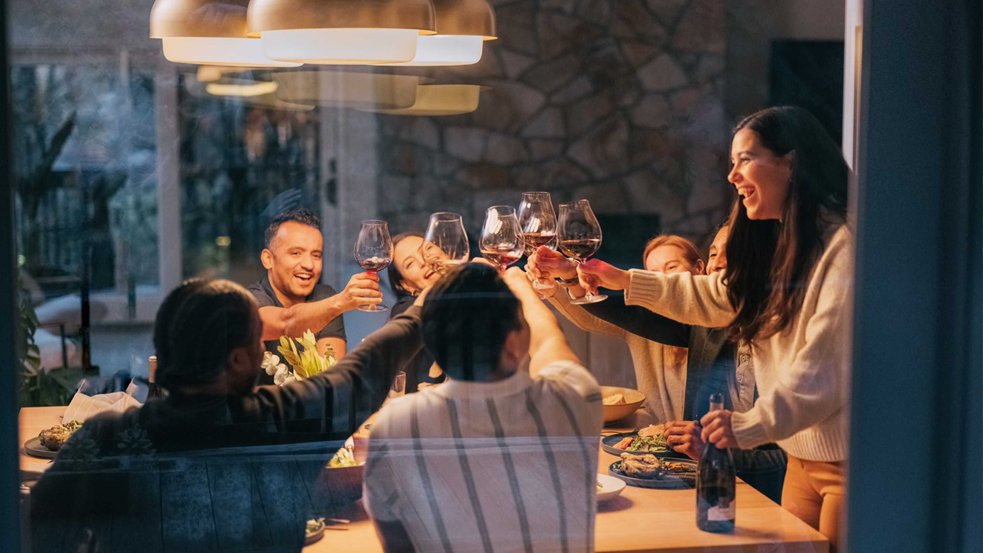 Group of young people enjoying a toast and cheers through a window.